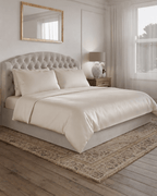 Oatmeal bedding set on a bed in a bedroom with a lamp and mirror.