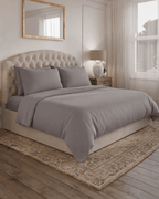 Warm Grey bedding set on a bed in a bedroom with a lamp and mirror.