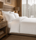Neatly made bed with white bedding in a well-lit bedroom.