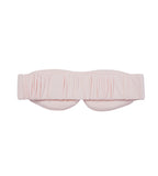 A light pink sleep mask with a gathered, pleated design across the top and a wide elastic strap, shown against a plain white background.