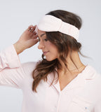 A woman wearing a light pink headband, posing against a light grey background.