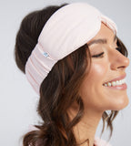 A woman wearing a light pink padded sleep mask