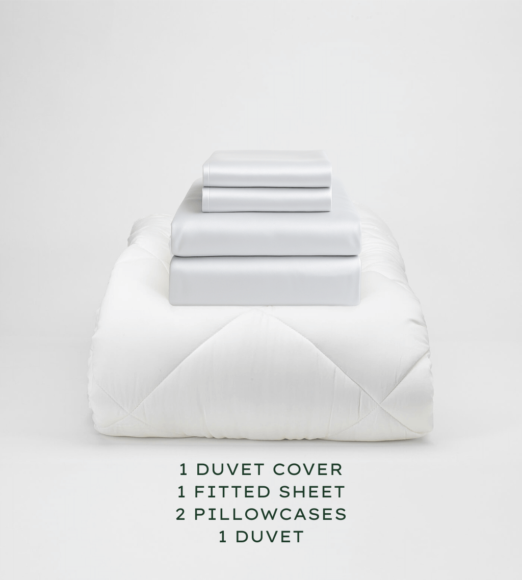 White bedding set with duvet, duvet cover, fitted sheet, and pillowcases on a white background.