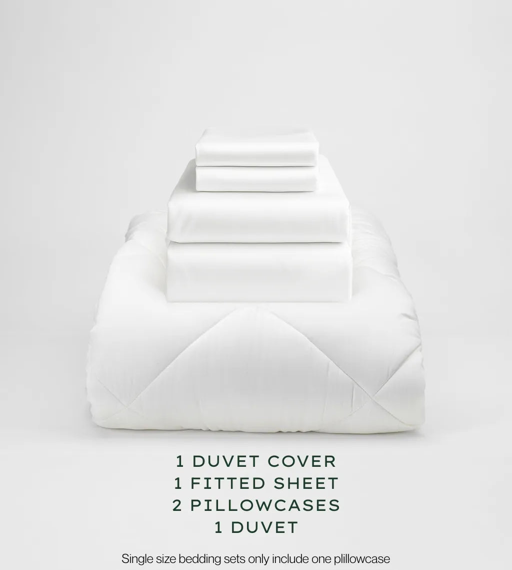 White bedding set with duvet, duvet cover, fitted sheet, and pillowcases on a light gray background.